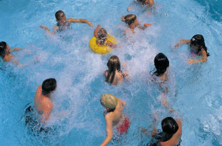 Children having a grand time playing in a clean pool, splashing and playing in the water.