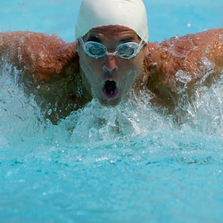 Swimmer racing in large public pool.